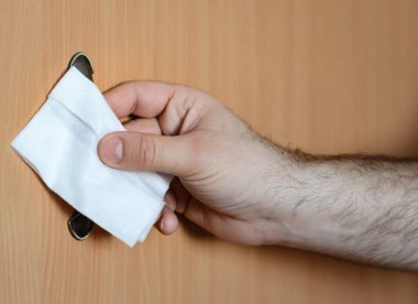 Evdeki mobilyaların saplarını antibakteriyel dezenfekte ile dezenfekte eden bir adamın eli..