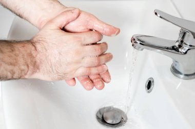 Alışveriş veya işten döndükten sonra ellerini yıkayan erkek. Bakteri ve kovid 19, işyerinde ve evde hepatit ve bakterilere karşı önlem ve koruma.