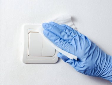 Eldivenleri silip temizleyen kadın. Ampul anahtarı. Bakteri ve covid-19 virüsü önleme yayıyor  .