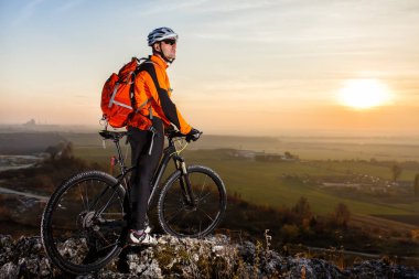 Bisikletçi dağ bisikleti hill izinde günbatımında ayakta görünümünü