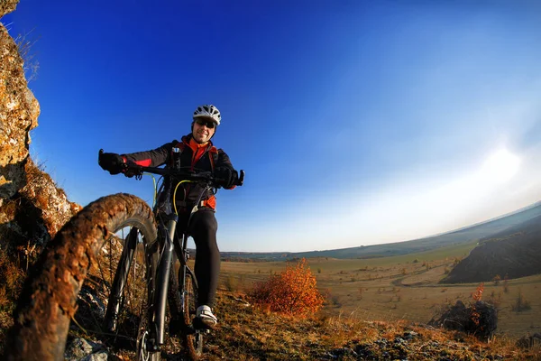 Vista a basso angolo del ciclista in mountain bike sul sentiero roccioso all'alba — Foto Stock
