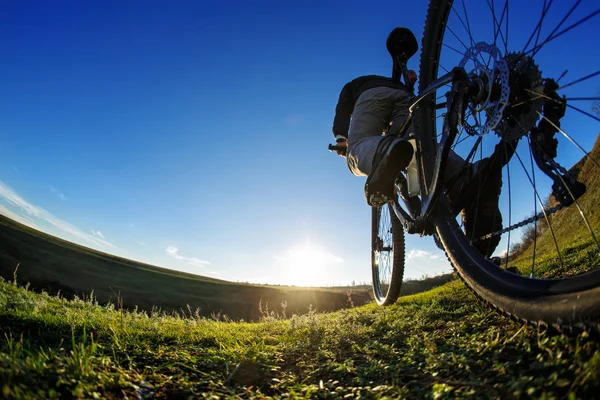 Részlet a kerékpáros férfi láb, hegyi biciklizés szabadtéri nyomvonal a napsütötte réten — Stock Fotó