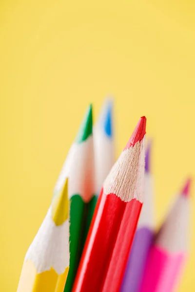 Nahaufnahme von Farbstiften mit unterschiedlicher Farbe über gelbem Hintergrund — Stockfoto