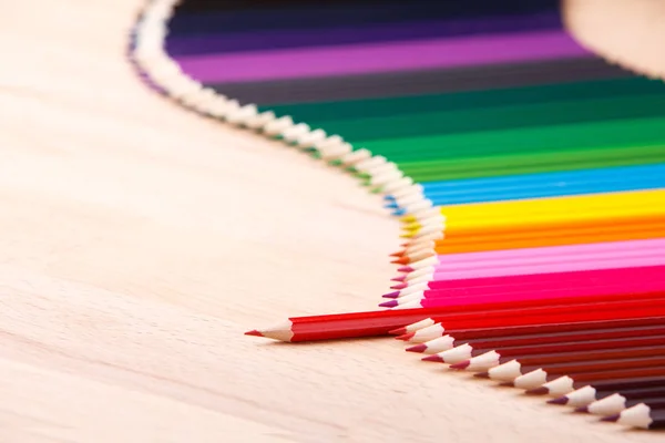 ベージュ色の木製のテーブルの上に色とりどり鉛筆。色鉛筆から波形罫線. — ストック写真