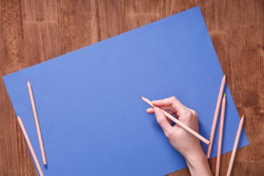 Kız el çizim, boş mavi kağıt ve renkli kalemler ahşap tablo