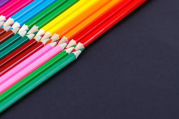 Lápis coloridos no fundo escuro deitado em cantos opostos — Fotografia de Stock