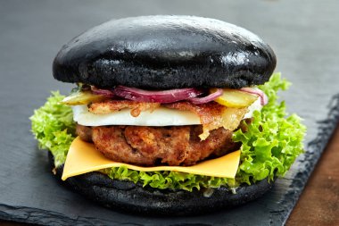 Taş Masa siyah arka plan üzerinde siyah hamburger. Fastfood yemek. Lezzetli Hamburger. Gurme hamburger.