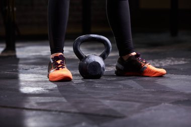 Genç kadın, bacaklar siyah tozluk, portakal spor ayakkabı ve kettlebell kırpılmış görüntü. CrossFit egzersiz