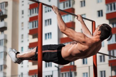 Uygun gönderme yapan genç erkek yatay çubuk açık havada ups