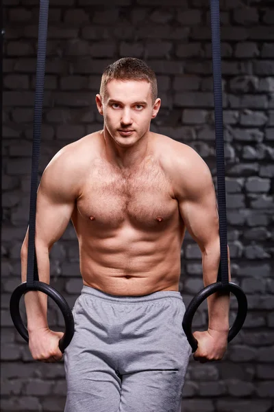 Crossfit-Kernübung. Entschlossener Mann trainiert im Fitnessstudio Klimmzüge mit Gymnastikringen für die Kraft — Stockfoto
