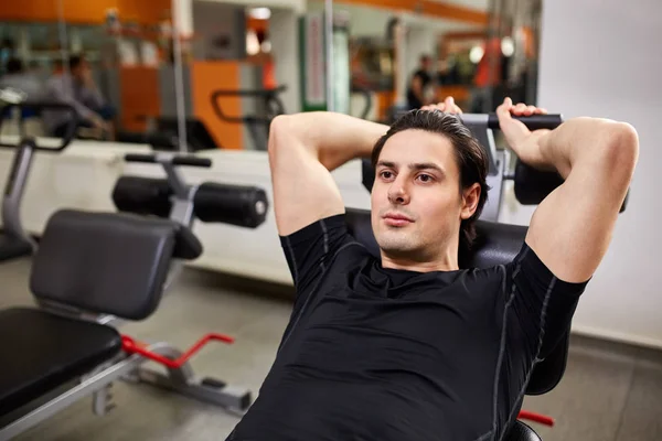 Fitness and Sport. Athletic man doing exercises with arm in gym