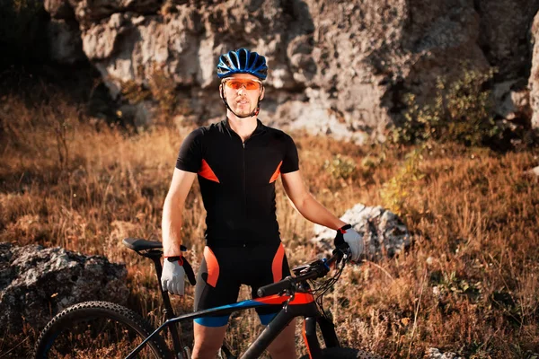 Retrato de un ciclista en casco y gafas de sol en una bicicleta de montaña. El deporte activo en la naturaleza . — Foto de Stock