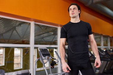 Siyah t-shirt ayakta simülatörü karşı spor salonunda yakışıklı kaslı adam portresi yaşam tarzı.