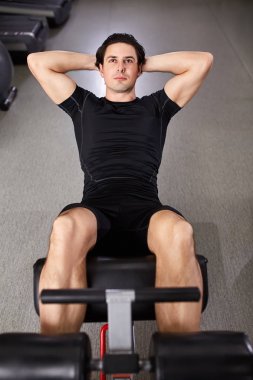 Spor salonunda simülatörü ile onun karın üzerinde siyah eşofman erkekte.