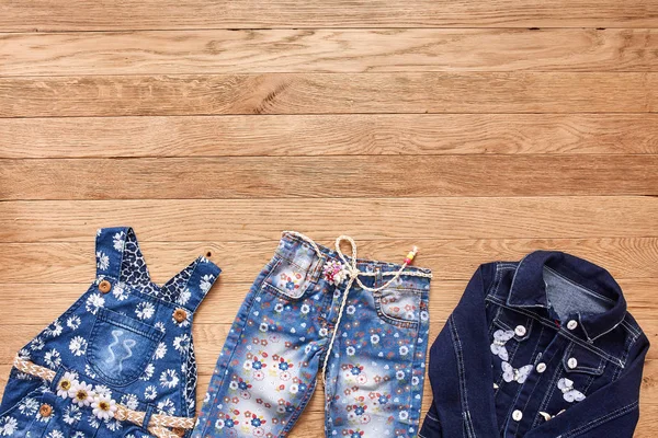 Calça infantil, jaqueta e vestido de ganga em fundo de madeira . — Fotografia de Stock