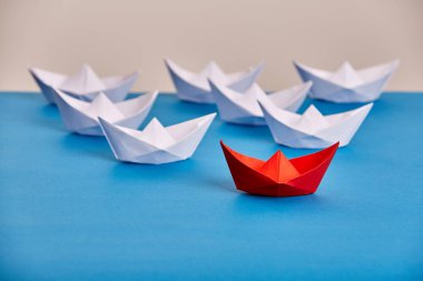 Parlak kırmızı kağıt gemi mavi ışık arka plan dayalı önde gelen Beyaz olanlar.