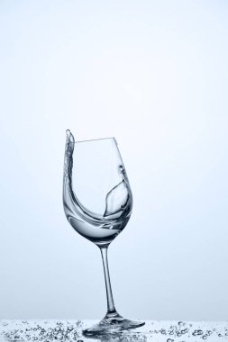 Hareket ettirildiğinde kadehinin karşı açık renkli cam üzerinde dururken temiz su ile gelen sıçramasına su.