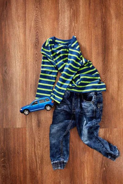 Vista superior de la ropa de los niños y el coche de juguete azul sobre fondo de madera . — Foto de Stock