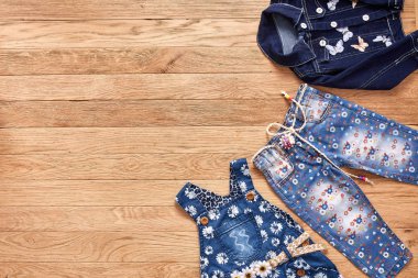 Çocuk kot pantolon, ceket ve kot ahşap arka plan üzerinde elbise.