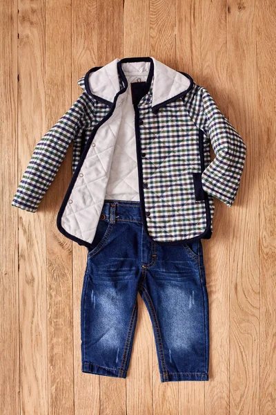 Jeans und Jacke für Kinder auf Holzgrund. — Stockfoto