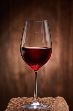Kırılgan ahşap stand ahşap duvar arka plan üzerinde kırmızı şarap kadehi.