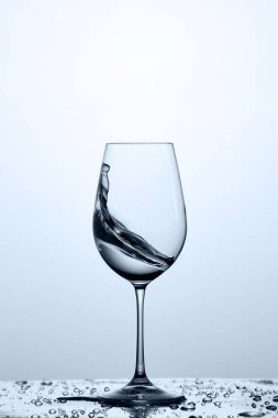 Kadehinin damlacıkları ışık arka plan ile camına şeffaf su sıçrama ile.