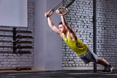 Spor salonu pull UPS haç tuğla duvara jimnastik halkalar ile çalışan genç atlet erkeğin spor salonu uygun.