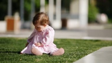 Mutlu bebek-kız parkta yeşil çimenlerin üzerinde oturan ve oyun.