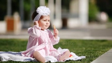 Yeşil çimenlerin üzerinde güzel kız bebek oturma ve parkta fırında yemek.