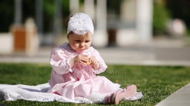 Yeşil çimenlerin üzerinde güzel kız bebek oturma ve parkta fırında yemek.