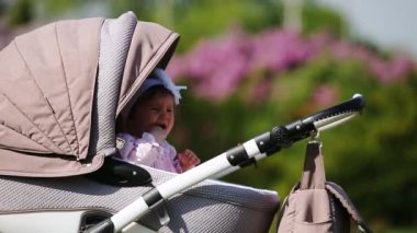 Kız bebek bebek arabası park güneş ışığı gün oturmuş ağlıyor.