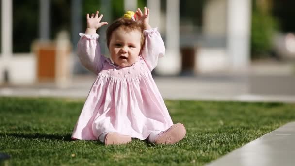 Happy-děvčátko sedící na zelené trávě v parku a hraje. — Stock video