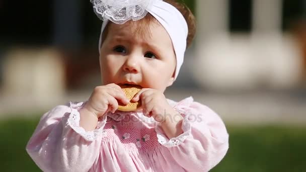 Close-up do bebê-menina bonito comer assar no parque em dia de luz solar . — Vídeo de Stock