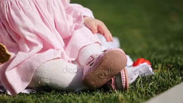 Nahaufnahme des schönen Baby-Mädchens, das auf dem grünen Rasen im Park sitzt. — Stockvideo