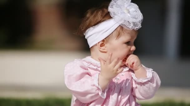 Close-up do bebê-menina bonito comer assar no parque em dia de luz solar . — Vídeo de Stock