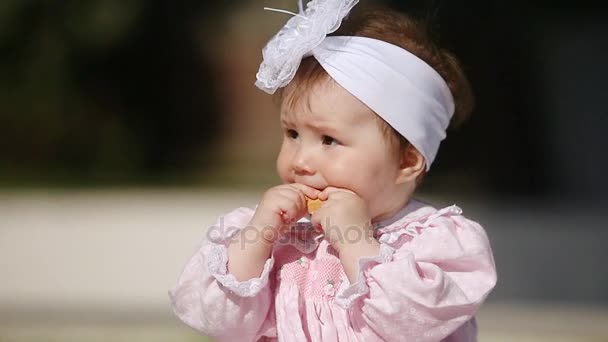 Gros plan de la mignonne petite fille qui mange au four dans le parc au soleil . — Video