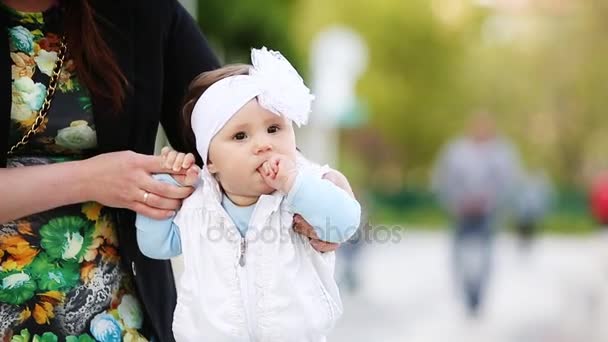 Primer plano una manos de madre sosteniendo lindo poco riendo chica en el parque . — Vídeo de stock