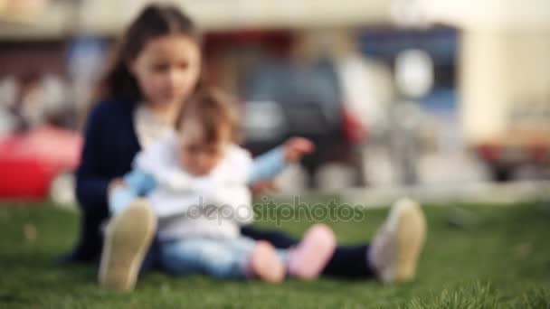 Duas irmãs adoráveis em uma grama verde em um dia ensolarado de verão no parque . — Vídeo de Stock