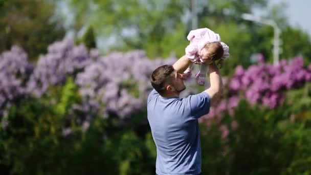 Šťastný otec drží málo holčičku v náručí a hrát společně v parku. — Stock video