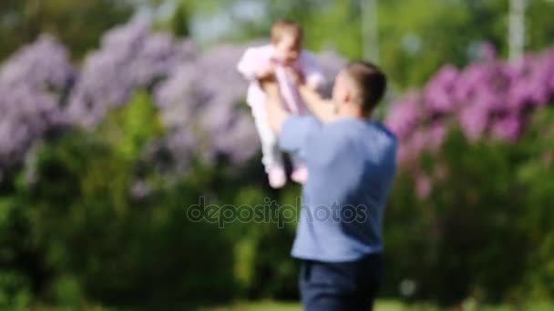 Lycklig far hålla lite baby-flicka i armar och spela tillsammans i parken. — Stockvideo