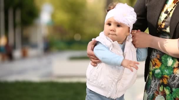 公園でかわいい少し笑っている女の子を持つお母さんの手のクローズ アップ. — ストック動画