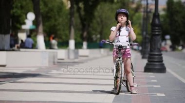 Şirin kız giyiyor kask ve güneşli günde bir bisiklet park gezintisi.