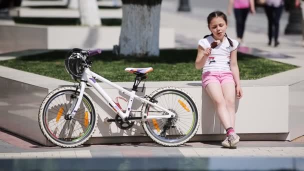 Cute little girl eating ice cream in the city park in sunshine summer day. — Stock Video
