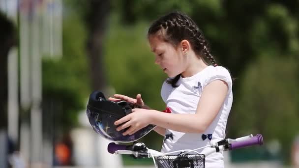 Primer plano de la chica con casco y luego monta una bicicleta en el parque de la ciudad . — Vídeo de stock