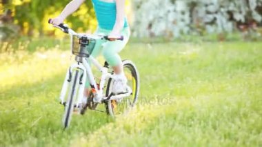 Mutlu küçük kız bir bisiklet sürme Şehir Parkı yeşil çim üzerinde açık.