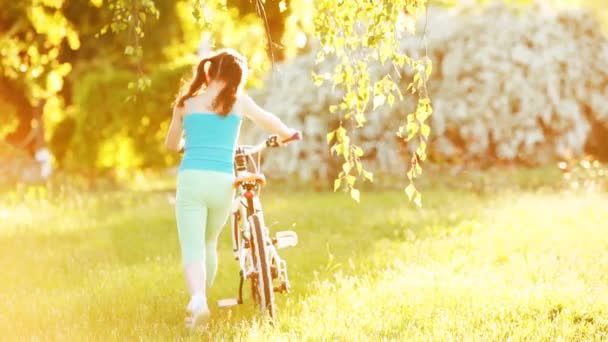 Happy little girl riding a bicycle on the meadow in summer sunshiny day. — Stock Video