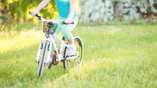 행복 한 어린 소녀는 자전거를 타고 도시 공원에서 푸른 잔디에 야외. — 비디오