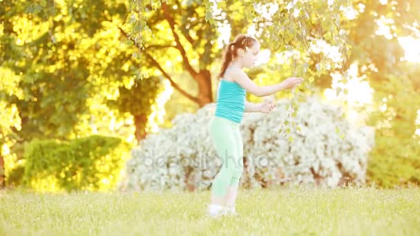 Roztomilá holčička chůzi pod stromem v parku na slunečný letní den. — Stock video