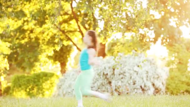 Schattig klein meisje lopen onder de boom in het park op zonnige zomerdag. — Stockvideo