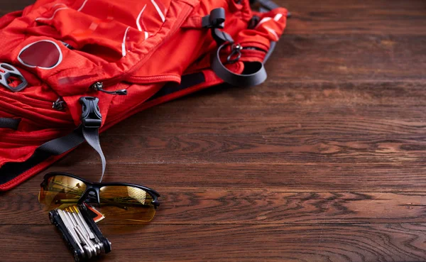 Toeristische rugzak, zonnebril en vistuig voor de fiets op de houten achtergrond. — Stockfoto